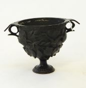 A bronze two-handled cup decorated with trailing foliage, on circular foot,