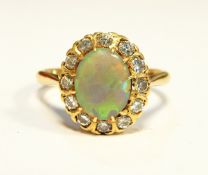 A gold, opal and diamond cluster ring, the central oval opal surrounded by 12 eight-cut diamonds,