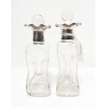 A pair of glass scent bottles of waisted form with silver lobed collars