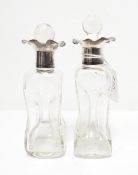 A pair of glass scent bottles of waisted form with silver lobed collars