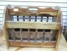 A stained wood handcrafted magazine rack with turned spindle gallery and a stained wood framed