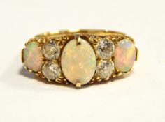 An 18ct gold, opal and diamond dress ring set three oval opals and four diamonds,