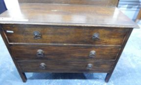 A stained wood chest of drawers with three long drawers below and a stained wood drop-leaf table