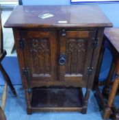 A dwarf oak cabinet enclosed by a pair of Gothic carved doors,