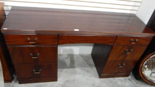 A reproduction mahogany kneehole desk having an arrangement of seven drawers