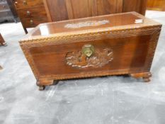 A small Oriental carved camphorwood chest on ogee bracket feet,