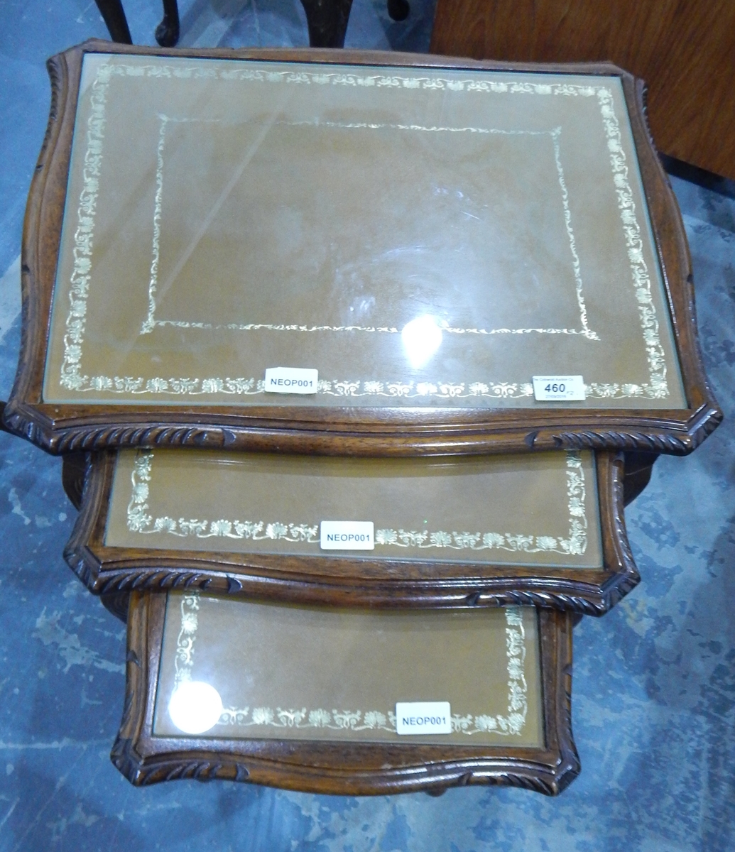 A nest of three mahogany tables inset tooled leather and glass covered topped and on slender