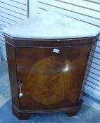 A mahogany bowfront corner cupboard with marbled top, raised on bracket feet,