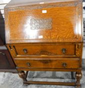 A 1930's oak bureau, the fall with carved ornamentation,