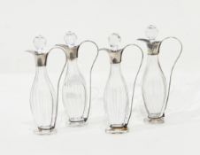 A set of four cut glass oil bottles and stoppers with silver plated mounts,