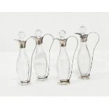 A set of four cut glass oil bottles and stoppers with silver plated mounts,