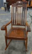 An Oriental carved hardwood rocking chair with pierced lattice crest rail and splat