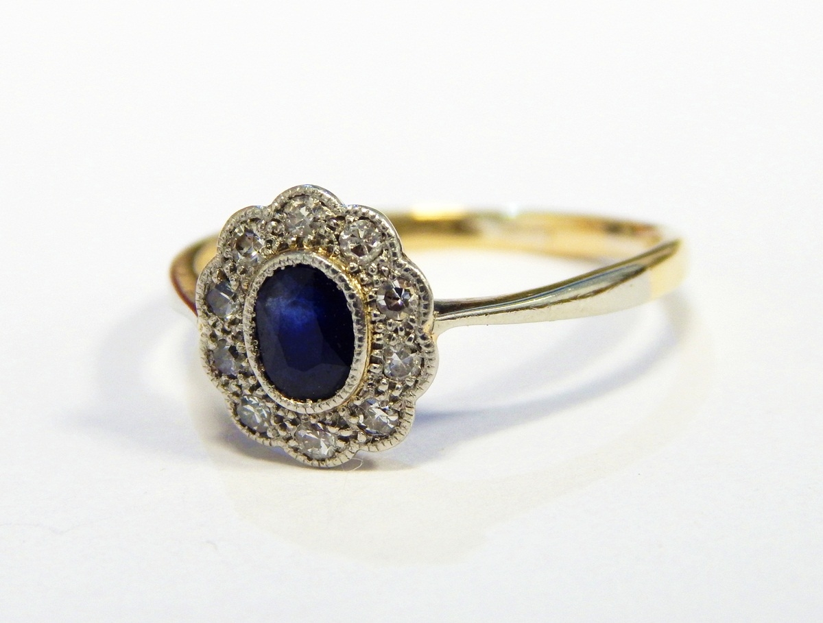 Sapphire and diamond cluster ring set oval facet-cut sapphire and surround of ten tiny diamonds,