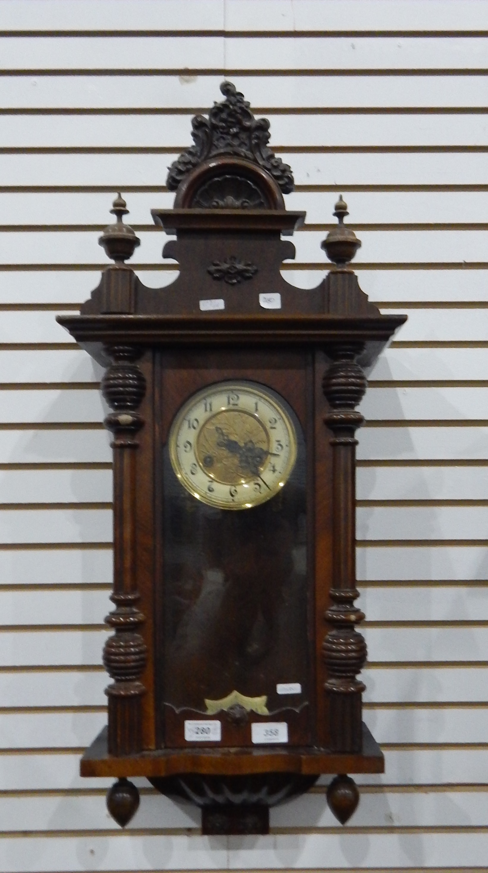 An Edwardian mahogany Vienna-style wall clock with Arabic numerals, carved pediment,