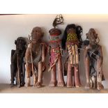 Three carved African wooden figures of seated men with earrings and two African naive carved