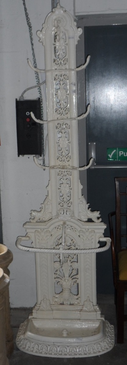 A cast iron coat rack with seven coat hangers and umbrella stand to base,