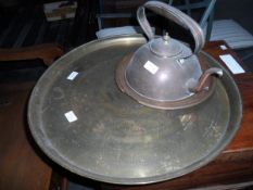 A circular copper table with Middle Eastern writing together with copper plate and kettle
