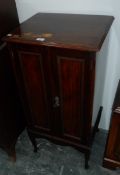 A stained mahogany sheet music cabinet with bead border on door panels, serpentine apron,