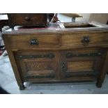 An oak sideboard with tiled top and raised backpiece, on square tapering legs,