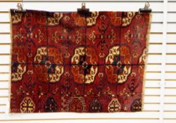 A fragment of a Tekke rug with geometric designs, on red ground,