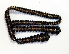 A French jet and gilt metal crossover necklace with faceted beads