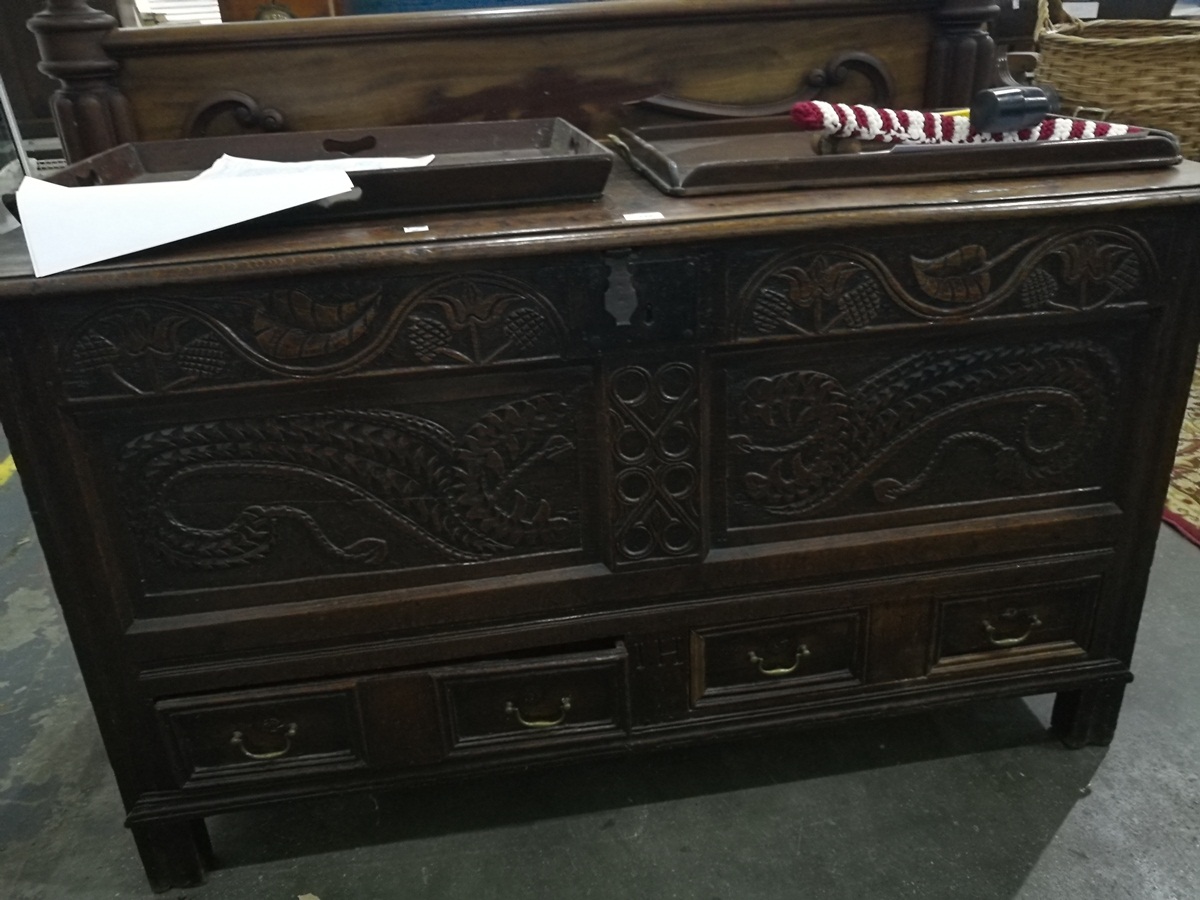 An 18th century oak mule chest with floral carved decoration and carved dragons, drawers to base,