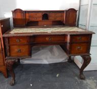A mahogany kneehole desk with fabric insert with stationery drawers and two flanking cupboards,