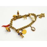 A charm bracelet marked 14ct with assorted charms including an enamelled figure of an accordion