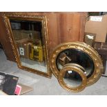 A gilt circular porthole shaped mirror and two others