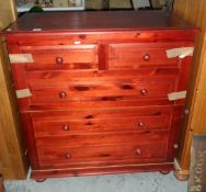 A red stained fold-out bed with faux drawer exterior,