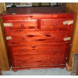 A red stained fold-out bed with faux drawer exterior,