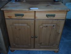A dwarf pine cupboard fitted two drawers over two panelled doors and on bun feet,