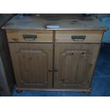 A dwarf pine cupboard fitted two drawers over two panelled doors and on bun feet,