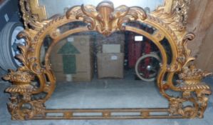 A giltwood overmantel mirror in rococo style with floral and scroll carving,