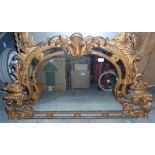 A giltwood overmantel mirror in rococo style with floral and scroll carving,