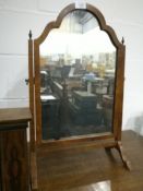 A walnut toilet mirror with domed top, finials to the uprights, on cabriole legs,
