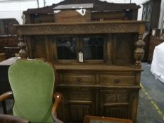 An reproduction oak court cupboard with floral decoration, three short drawers and three cupboards,