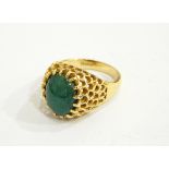 A gold-coloured ring with central green oval cabochon, with pierced mount,