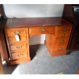 An oak writing desk with leather inset, seven short drawers,