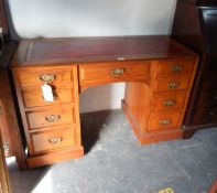 An oak writing desk with leather inset, seven short drawers,