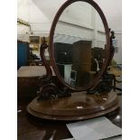 A mahogany toilet mirror on oval base, scroll supports,