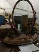 A mahogany toilet mirror on oval base, scroll supports,