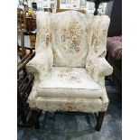 A wingback chair covered in white floral pattern,