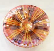 A large modern glass bowl decorated with browns and golds on a red ground,