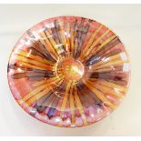 A large modern glass bowl decorated with browns and golds on a red ground,