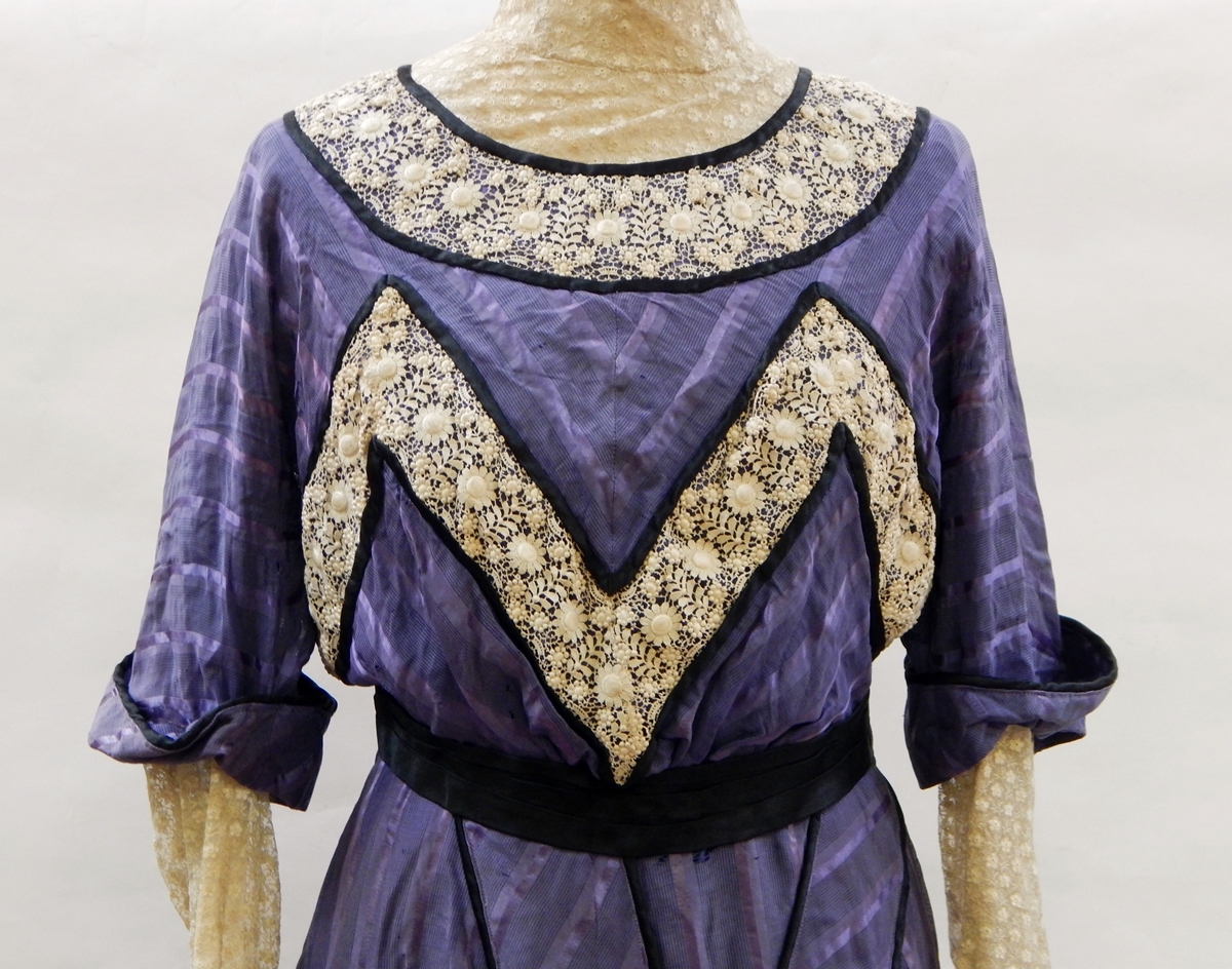 An early Victorian walking dress in purple silk, lace inset sleeves,