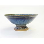 A studio pottery bowl of circular form, on pedestal foot, decorated in a mottled purple glaze,