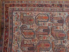 An Eastern rug, the central field decorated with botehs, on ivory ground within multiple borders,