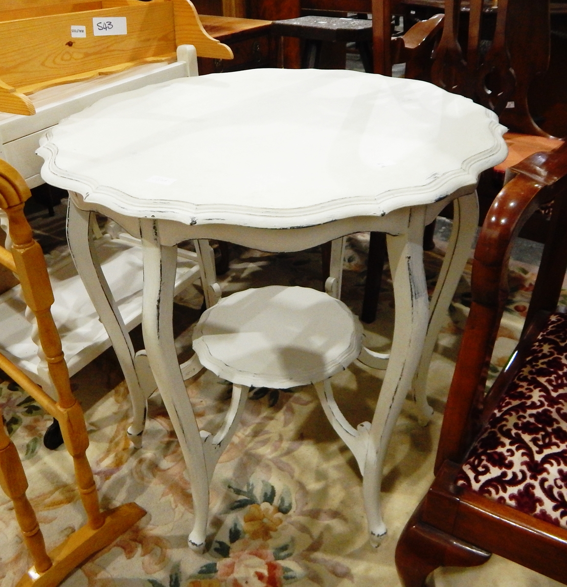 A white painted piecrust top table on cabriole legs united by under-shelf,