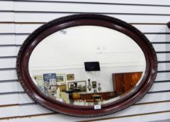 A Victorian oval bevelled plate wall mirror within a moulded scrolled frame,